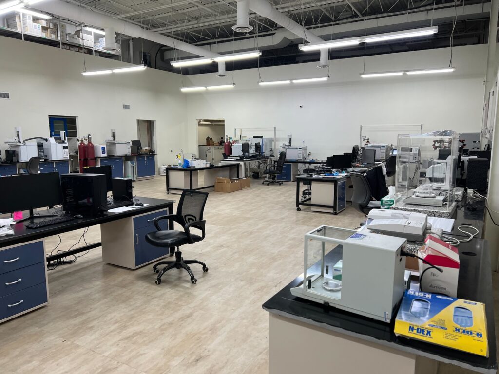 Wide view of PPB Analytical laboratory equipped with gas chromatographs, balances, computers, and workstations.