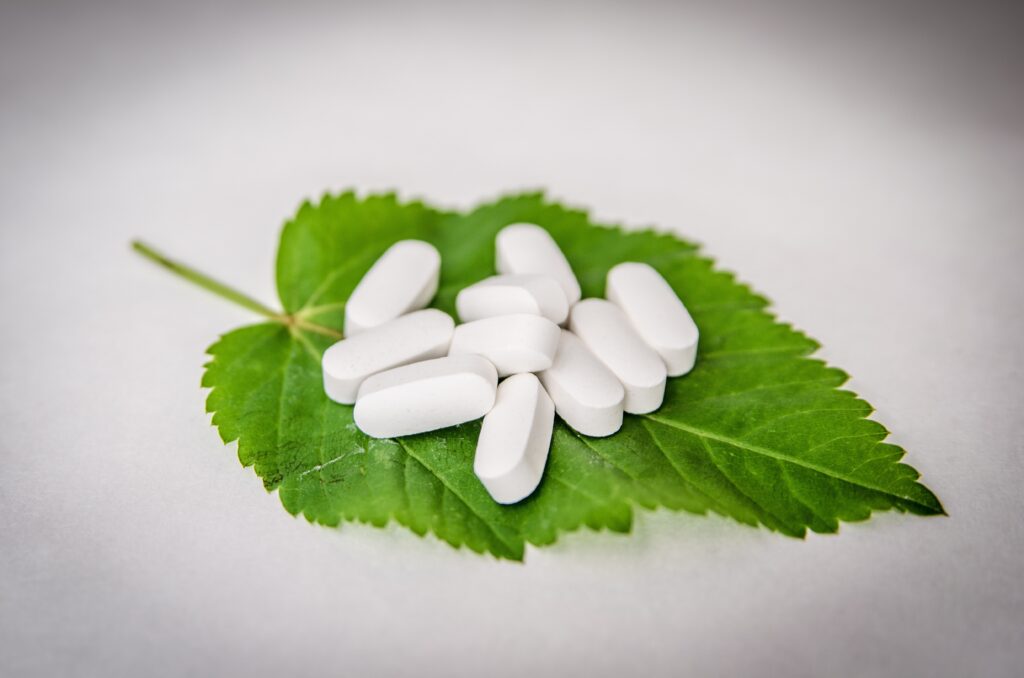Nutraceutical tablets on a green leaf.